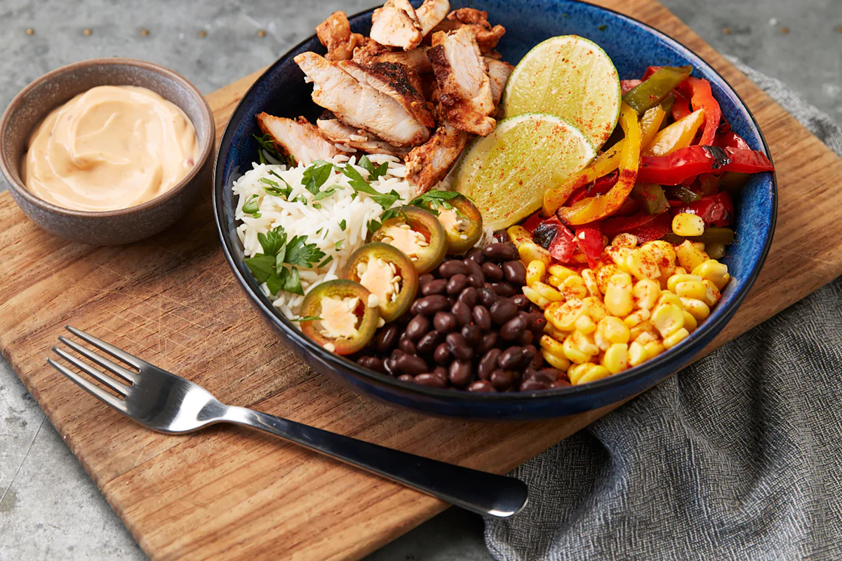 A bowl of chicken, black beans, sweetcorn, peppers and jalapeños with lime