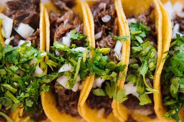 Close view of tacos topped with chopped onion and coriander